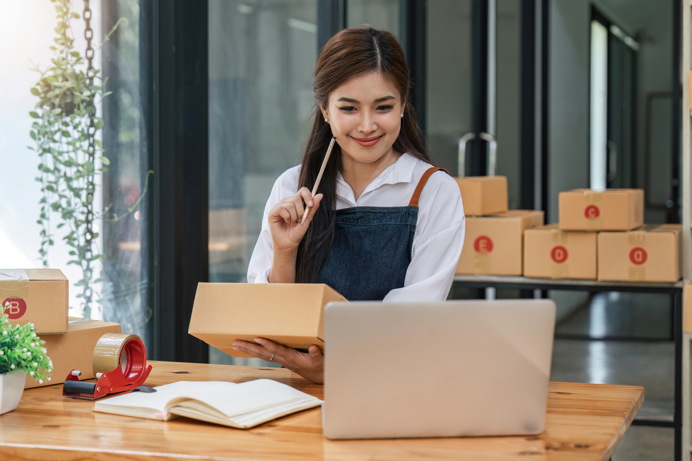 Woman who e-commerce business is writing a list of customers on paper before shipping to them, she runs an e-commerce business on websites and social media. Concept of selling products online